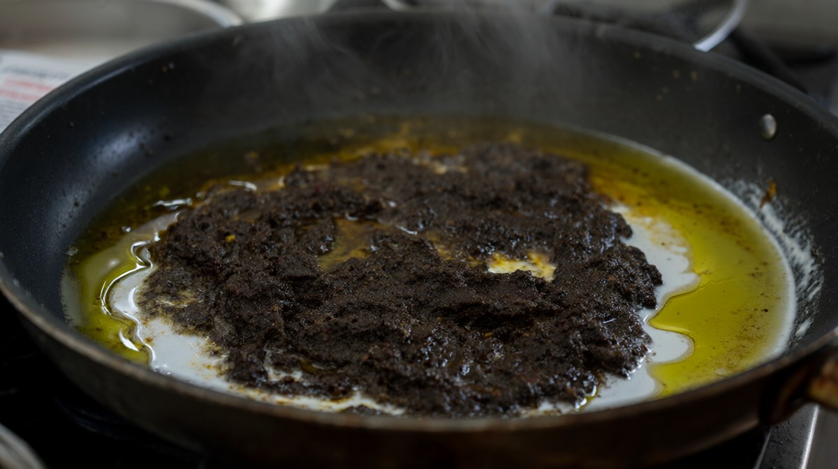 Curry paste frying in coconut cream with the oil clearly splitting and pooling at the edges