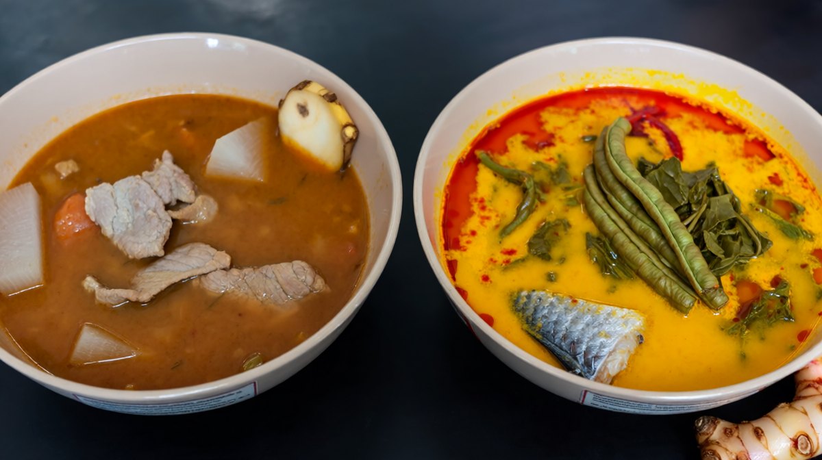 Two bowls of Thai sour curry side by side, a reddish Central version with daikon and a yellow-orange Southern version with chilli oil and fish