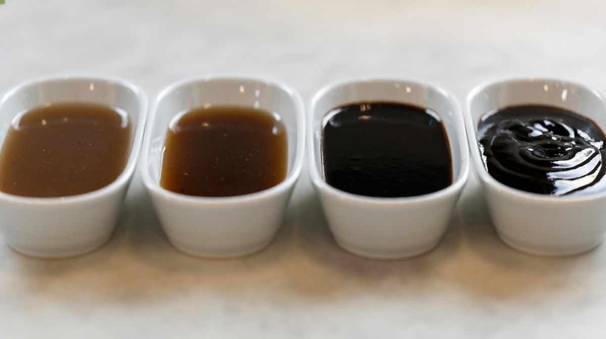 Four bowls in a row of dark glossy sauces from thin brown through to thick near-black
