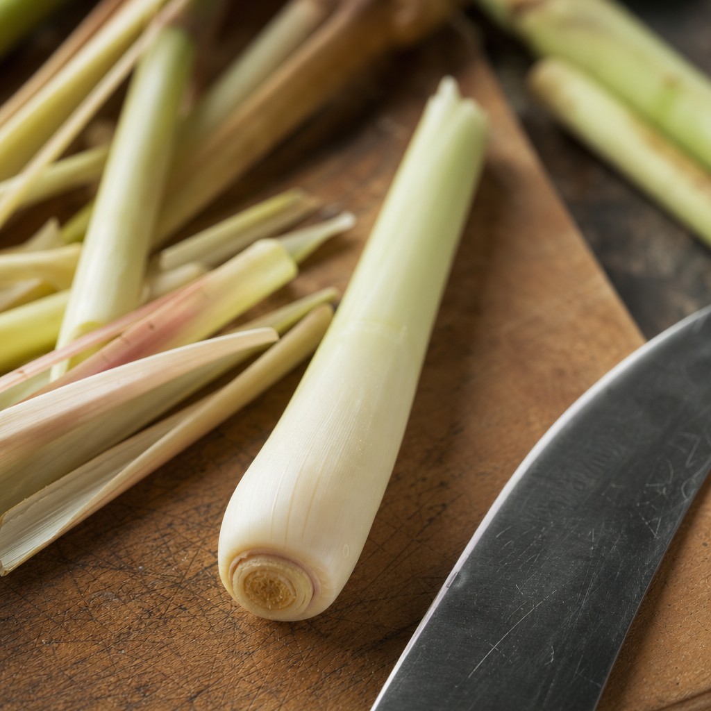 Fresh lemongrass stalks on a wooden board — showing pale cream base, dry outer layers, and vivid green tops