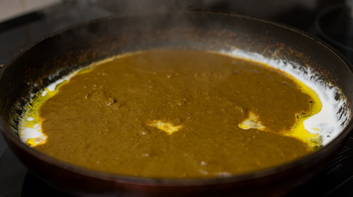 Curry paste frying in coconut cream with the oil separating and splitting at the edges of the sauce